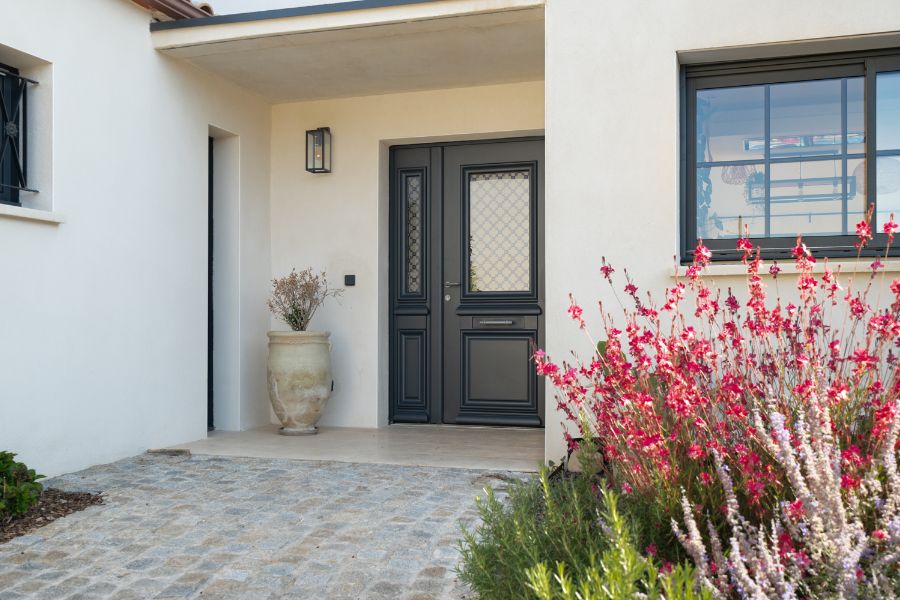 entrée de maison extérieure avec une allée pavée et des végéteaux colorés aux alentours