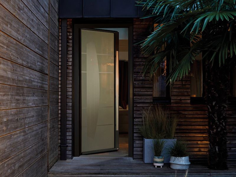 porte d'entrée vitrée moderne avec un vitrage sablé avec une barre de tirage sur une maison en bois