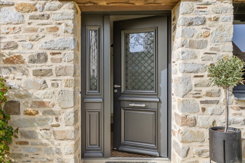 maison en pierre avec une porte d'entrée en aluminium au style traditionnel avec des moulures, une cimaise, une grille et un baton de maréchal