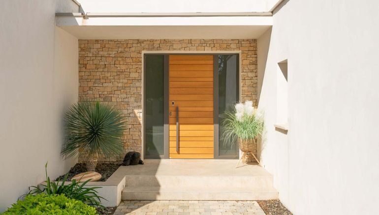 porte d'entrée en bois moderne modèle belcastel sur une maison avec parement de pierre