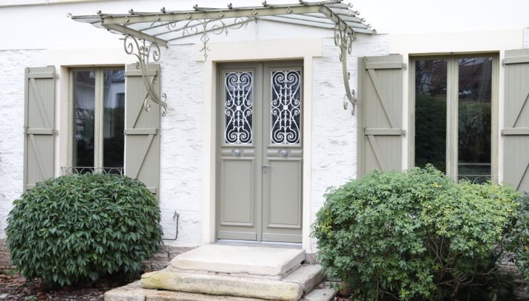 porte d'entrée sur mesure en bois sur une maison en pierres blanches